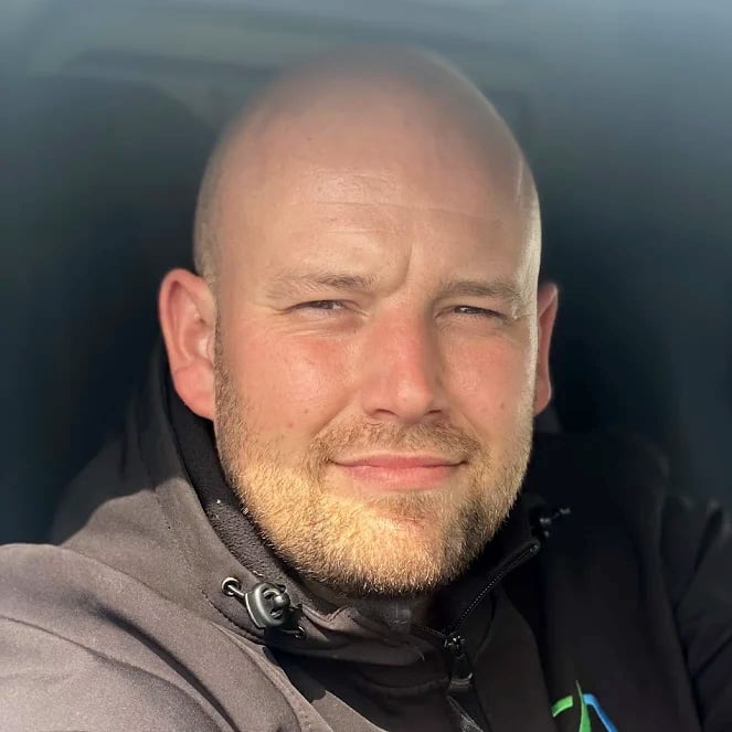 Bald man smiling in sunlight inside a car